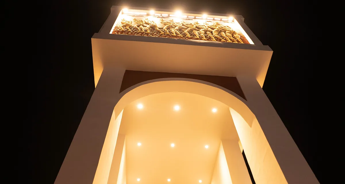 La Porte du Non-Retour de Ouidah éclairée la nuit, bas-relief des captifs en marche vers la mer