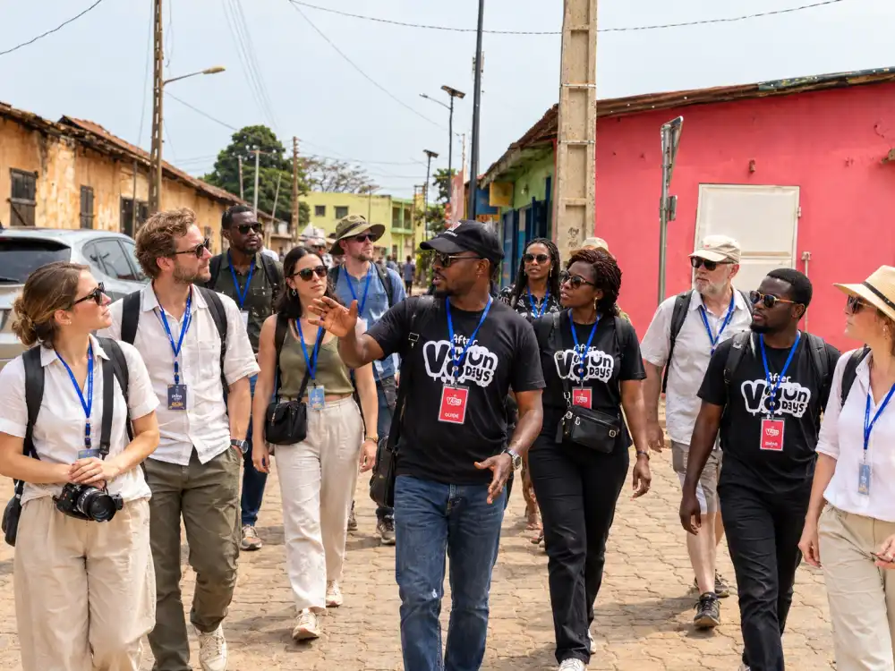 Image d'illustration : un guide After Vodundays explique la ville à son équipe dans une rue de Ouidah